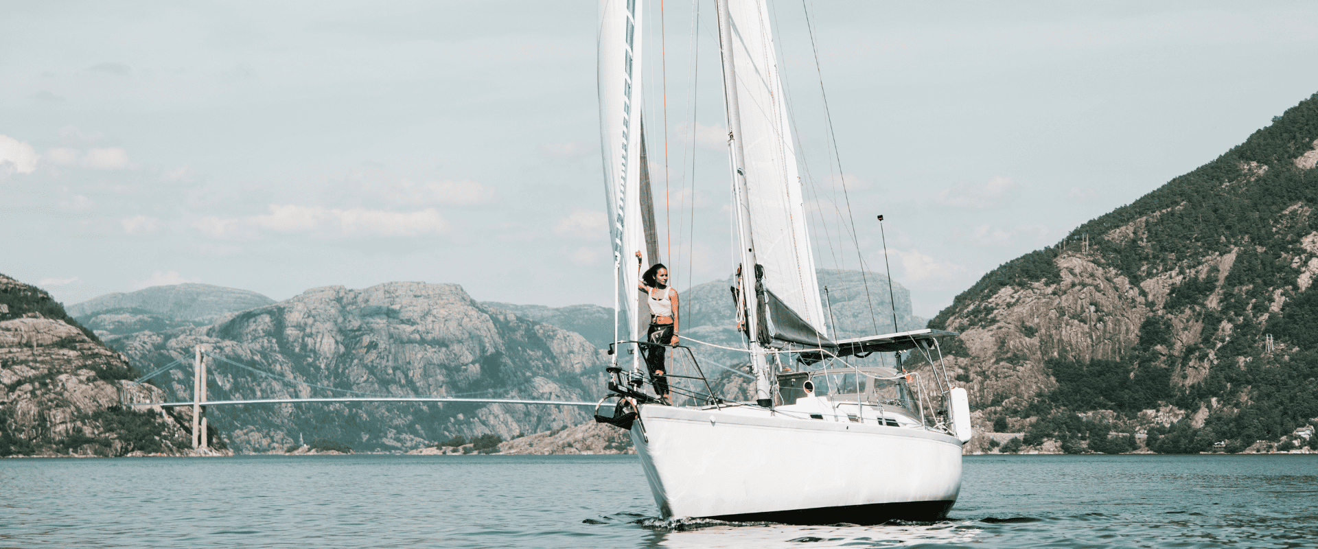 Sailing UMA’s 50-year-old sailboat Uma 3.0 on open water with mountains in the background.